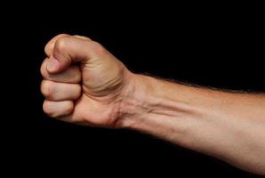 Male fist on a black background. Symbol of resistance and willpower. photo