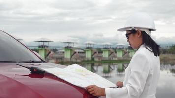 Female engineer in a white helmet reading data in a blueprint and using radio communication at the dam construction site to generate electricity. Clean energy and Technology concepts. video