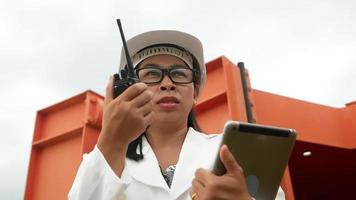 Female engineer in a white helmet holds a digital tablet and using radio communication at the dam construction site to generate electricity. Clean energy and Technology concepts. video