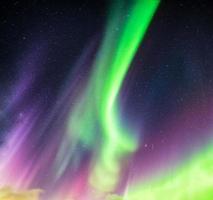 aurora borealis o luces del norte de colores verde y morado con estrellas en el cielo nocturno foto