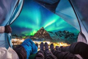 grupo de escaladores están dentro de acampar con auroras boreales sobre la montaña foto