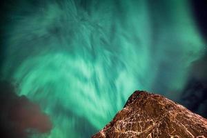 Aurora Borealis Northern lights dancing on steep mountain in sky