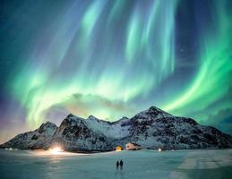 Fantastic Aurora borealis with starry dancing over snow mountain photo