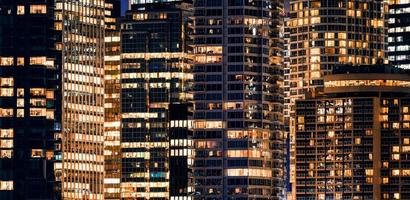 Facade windows of illuminated modern skyscraper with office building at night photo