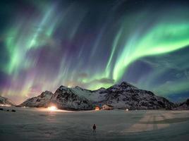 Fantastic Aurora borealis over snowy mountain with man standing photo