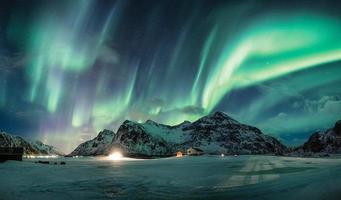 Aurora boreal o auroras boreales sobre la montaña nevada en la costa foto