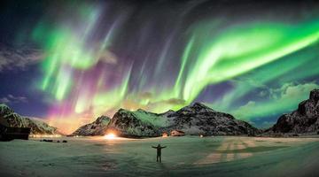 aurora boreal, auroras boreales sobre la montaña con una persona foto