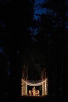 wedding banquet area in a pine forest with an arch against the background for several people photo