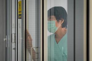 A senior lonely asian woman patient infected with covid-19 or coronavirus was admitted and quarantined in the isolation room in hospital photo