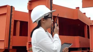 ingeniera con un casco blanco sosteniendo una tableta digital y comprobando el equipo en el sitio de construcción de la presa para generar electricidad. video