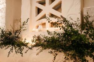 el presidium de los recién casados en el salón de banquetes del restaurante está decorado con velas y plantas verdes