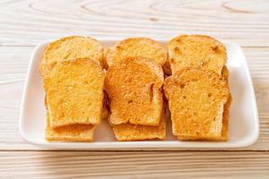 Baked crispy bread with butter and sugar on plate photo