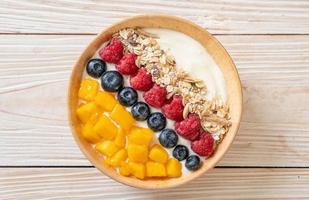 Homemade yogurt bowl with raspberry, blueberry, mango, and granola - healthy food style photo