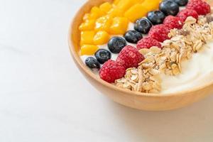 Homemade yogurt bowl with raspberry, blueberry, mango, and granola - healthy food style photo