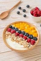 Homemade yogurt bowl with raspberry, blueberry, mango, and granola - healthy food style photo