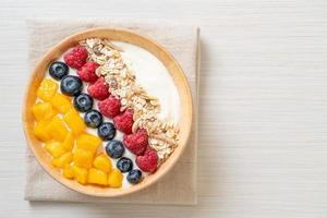 Homemade yogurt bowl with raspberry, blueberry, mango, and granola - healthy food style photo