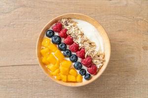 Homemade yogurt bowl with raspberry, blueberry, mango, and granola - healthy food style photo