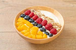Homemade yogurt bowl with raspberry, blueberry, mango, and granola - healthy food style photo