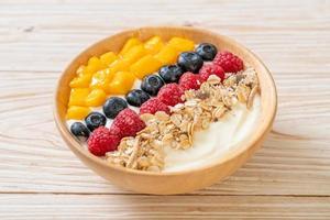 Homemade yogurt bowl with raspberry, blueberry, mango, and granola - healthy food style photo