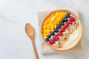 Homemade yogurt bowl with raspberry, blueberry, mango, and granola - healthy food style photo