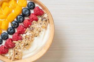 Homemade yogurt bowl with raspberry, blueberry, mango, and granola - healthy food style photo