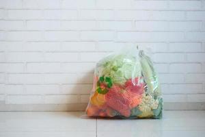 Flechas recicladas firman en una bolsa de compras con vegetales en un piso foto