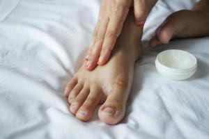 Mujer aplicando vaselina en los pies en la cama