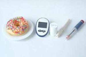 Herramientas de medición de diabetes, insulina y donas sobre fondo blanco. foto