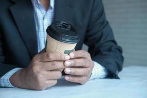 Businessman hand holding take away paper cup white sited photo