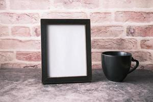 Empty frame and a coffee mug on wooden background photo