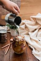 Barista pouring milk into a glass of iced coffee photo