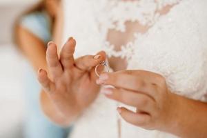 the bride gently touches her dear engagement ring photo