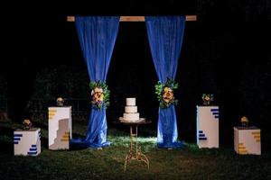 Pastel de boda en un banco de madera con un fondo de cascada foto