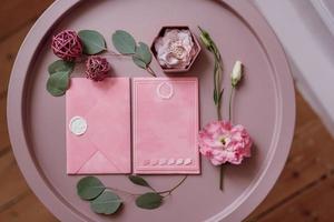 wedding invitation in a gray envelope on a table with green sprigs photo