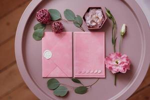 invitación de boda en un sobre gris sobre una mesa con ramitas verdes foto