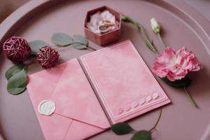 wedding invitation in a gray envelope on a table with green sprigs photo