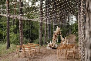 Área de ceremonia de boda con flores secas en un prado en un bosque de pinos foto