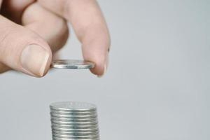Woman's hand put silver money coins to stack. photo