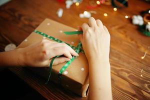 Women's hands tying ribbon on Christmas gift.