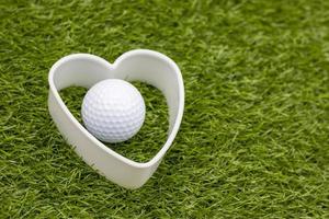 Golf ball with white heart are on green grass photo