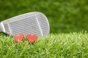 Two red hearts of golfer with iron back ground on green grass photo