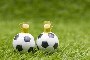 Balón de fútbol con vasos de cerveza sobre la hierba verde