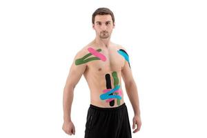 Atleta profesional masculino con cinta de kinesiología en el vientre y el hombro. deporte y rehabilitación, tratamiento de kinesioterapia