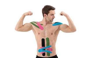 Male professional athlete with kinesiology tape on belly and shoulder. Sport and rehabilitation, kinesiotherapy treatment