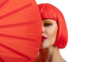 Beautiful girl wearing red wig holding red fan isolated on white background