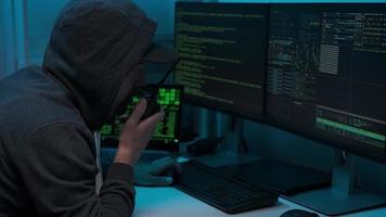 pirata informático escribiendo código en el teclado trabajando tarde en la noche y sin pasar por la seguridad cibernética. el jugador usa un walkie-talkie foto