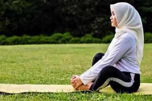 Young Muslim woman doing muscle stretching before doing yoga moves photo