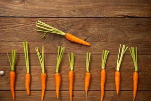Fresh baby carrots on wooden cutting board and wooden background photo