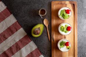 Vaso de cereza y aguacate en rodajas de yogur sobre fondo de madera foto