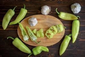 Green hot chili peppers and chili sliced with garlic on wooden background photo